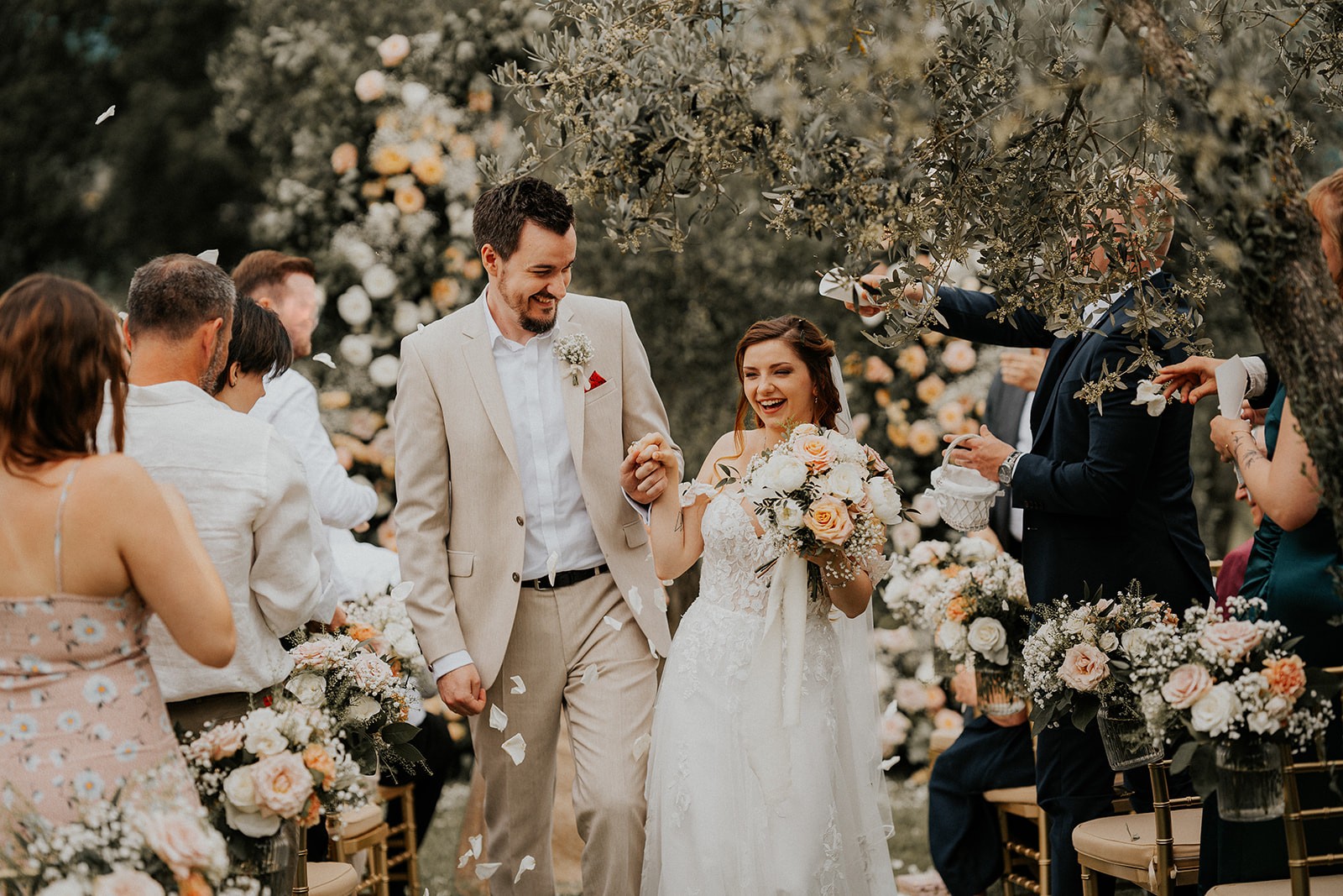 Glückliches Hochzeitspaar beim Auszug nach der Trauung in der Toskana, Blütenblätter werden geworfen.