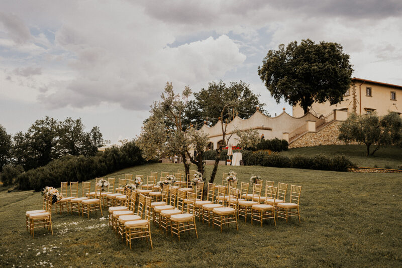 Aufnahme des Trauplatzes vor der Villa in der Toskana. Romantisches Setting mit goldenen Chiavari Stühlen.
