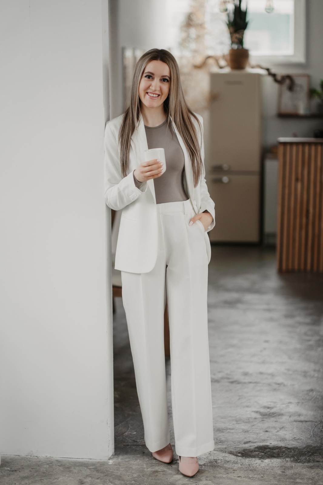 Hochzeitsplanerin mit Kaffeetasse im Gesprächsraum, entspannt und professionell.